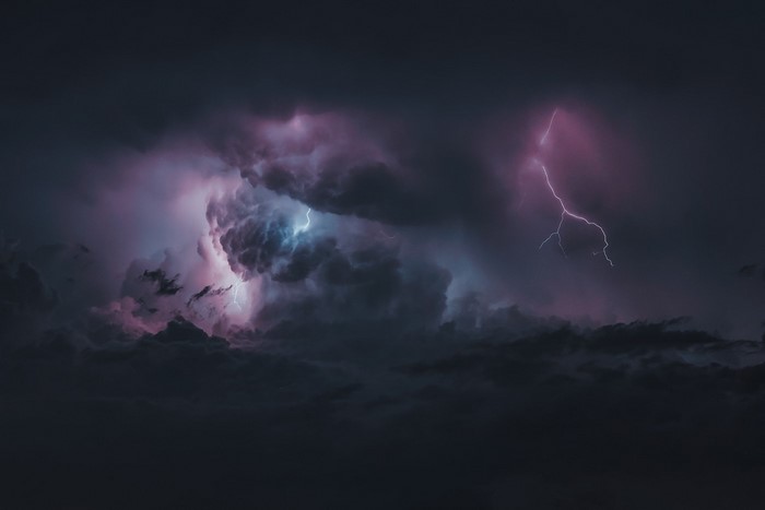 Lightning strikes through dark storm clouds
