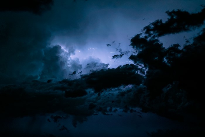 Lightning strikes through dark storm clouds