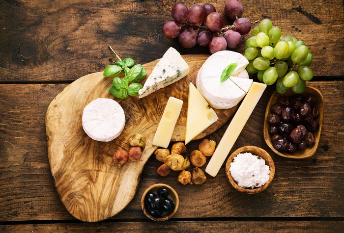Cheese board with grapes, olives, and dried fruit