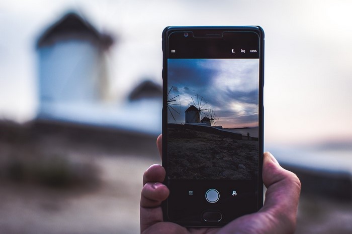 Smartphone photographing windmills at sunset