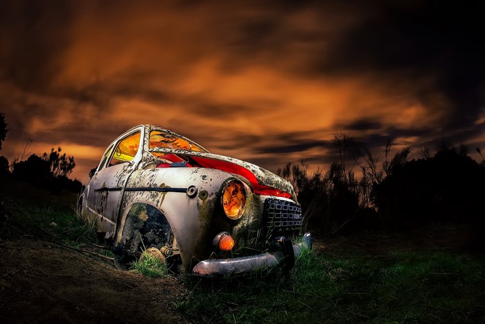 Abandoned car in a dark, cloudy landscape
