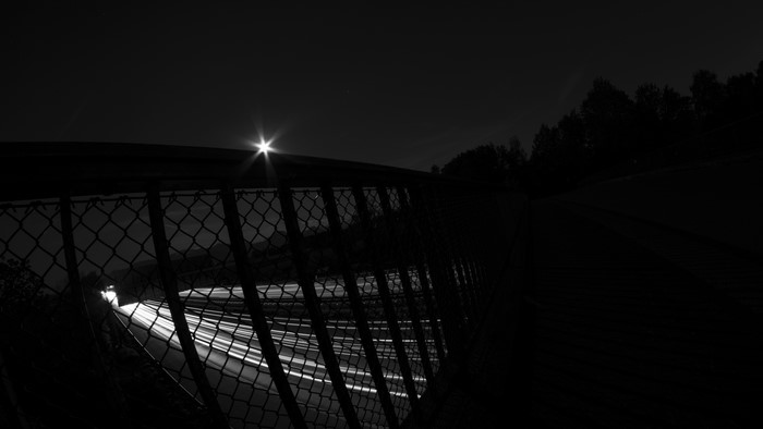 Monochrome long exposure of car lights on a road at night