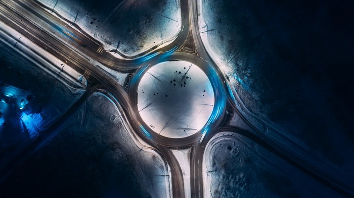 Aerial view of a snowy roundabout with light trails at night