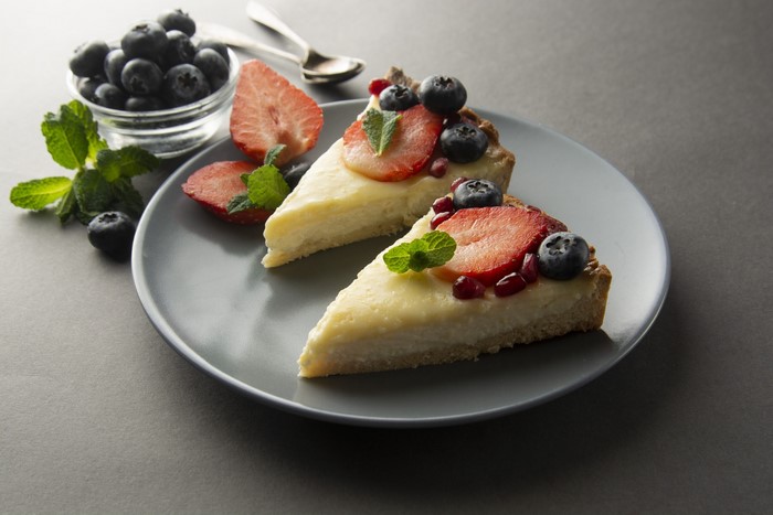 Two slices of fruit tart with berries and mint