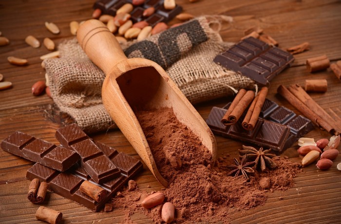 Chocolate, cocoa powder, cinnamon, and peanuts on a wooden table