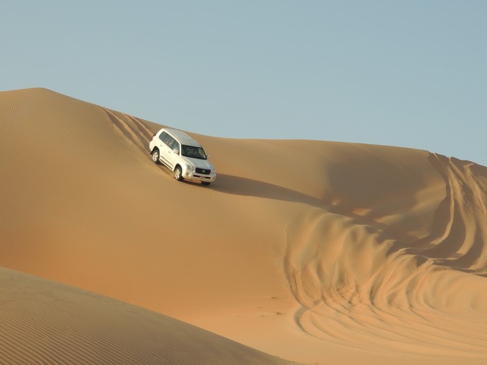 White Toyota Land Cruiser driving on sand dunes
