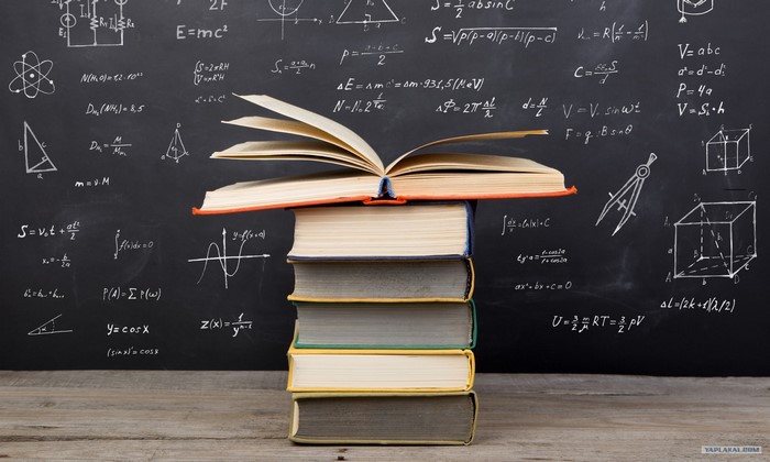 Stack of books on a blackboard with math formulas
