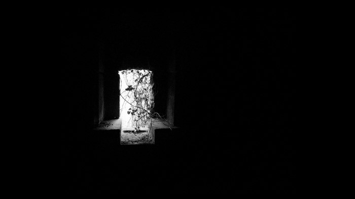 Monochrome image of a dark room with a window