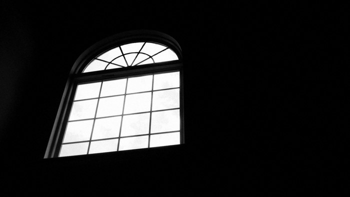 Monochrome arched window in darkness