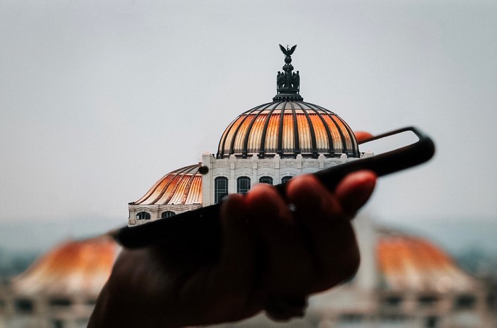 Hand holding smartphone with building dome reflection