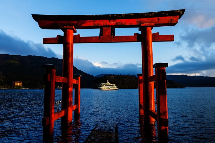 Red Torii gate on a lake with a boat in Japan