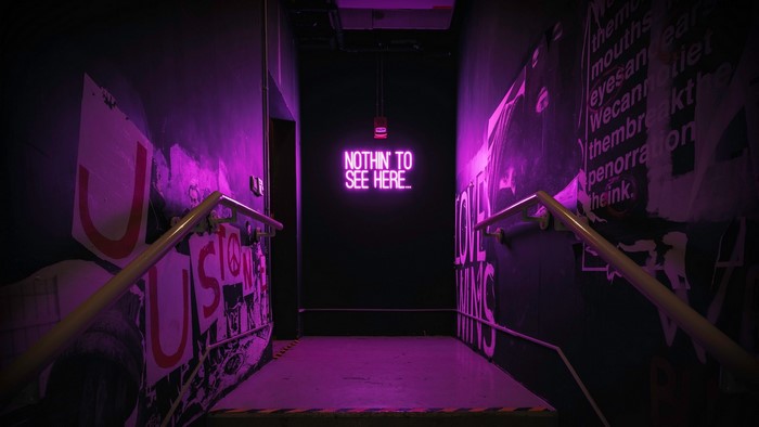 Neon sign in a dark hallway with purple lighting