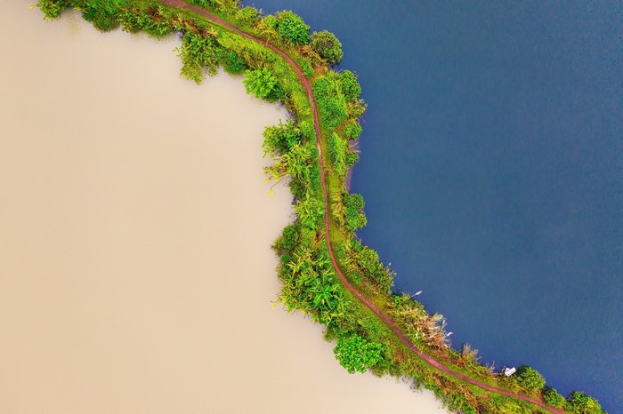 Aerial view of a path dividing two bodies of water with greenery