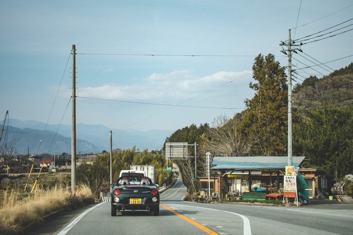 Black Daihatsu Copen driving on a road in Japan