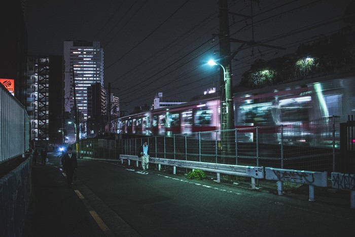 Train passing through a city street at night in Tokyo