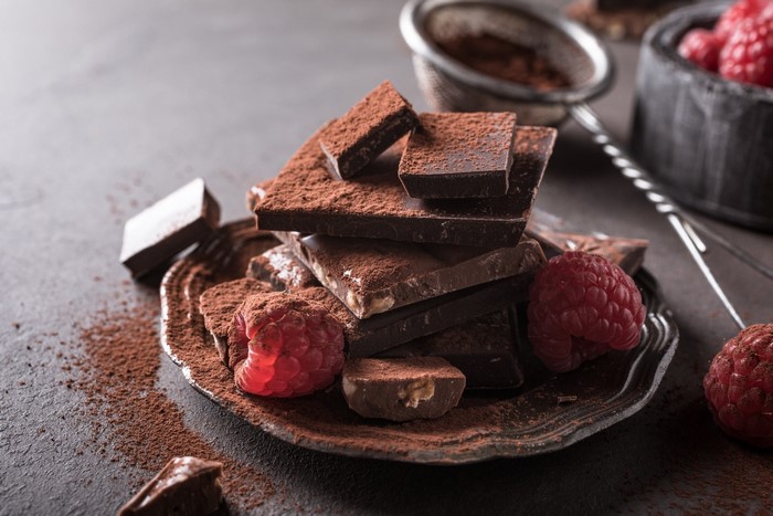 Chocolate pieces and raspberries on a dark surface