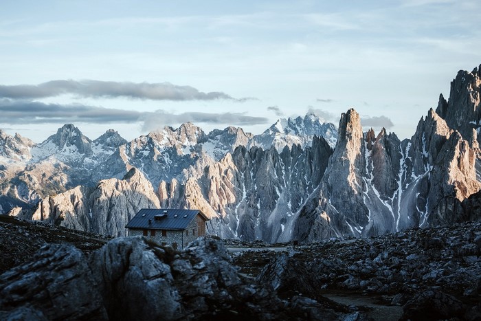 Stone hut in front of jagged mountains