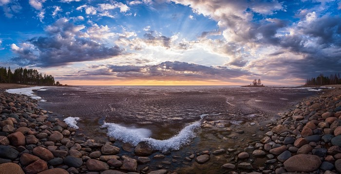 Rocky shore with ice and clouds at sunset