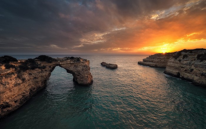 Sunset over rocky coast with sea arch