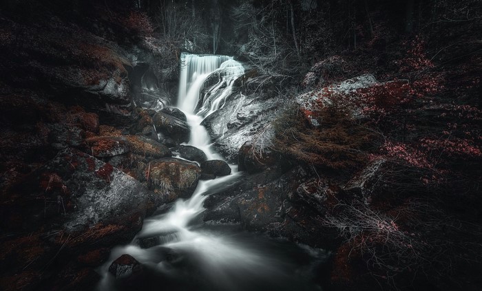 Waterfall cascading over mossy rocks in a dark forest