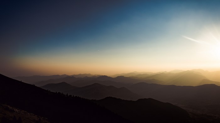 Sunset over layered mountains with blue and yellow sky