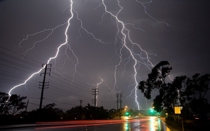 Lightning strikes over a wet road at night