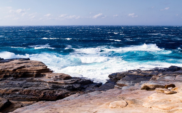 Waves crashing on rocky shore under a cloudy sky