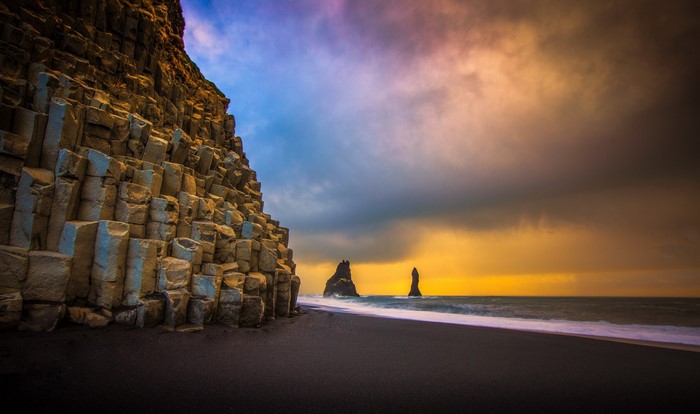 Basalt columns on a black sand beach with sea stacks