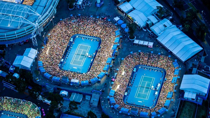 Aerial view of two tennis courts at night with crowds