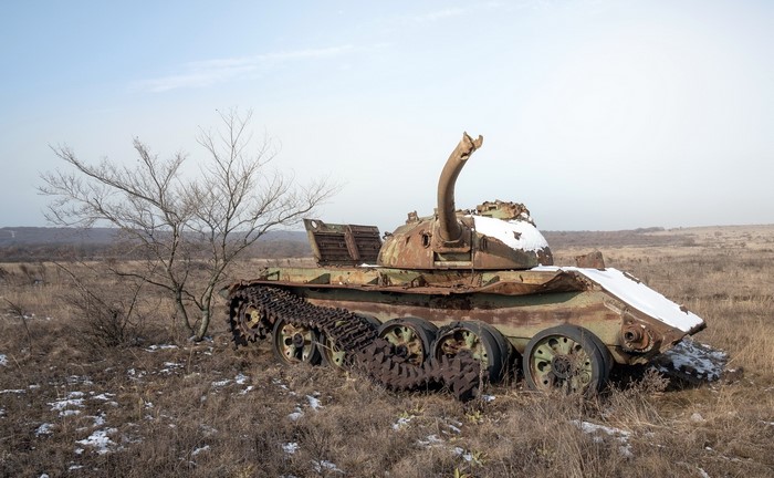 Abandoned tank wreck in a dry field with snow