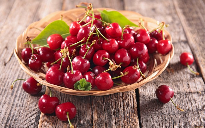 Cherries in a basket on a wooden surface