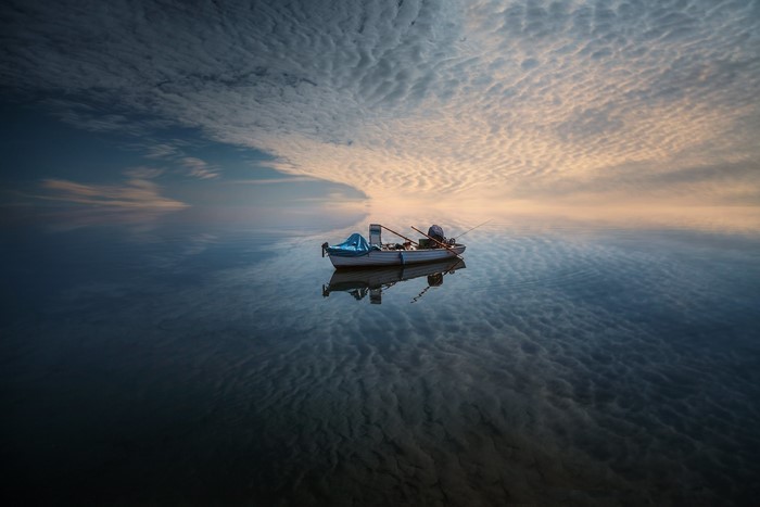 A fishing boat on calm water with dramatic clouds