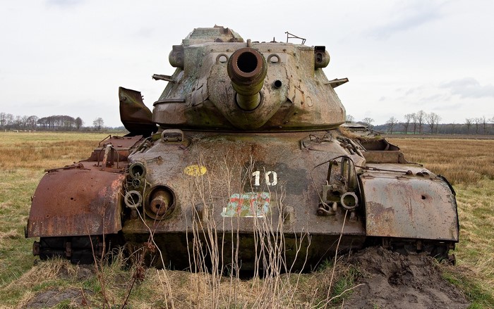 Abandoned rusty tank with number 10 in a field