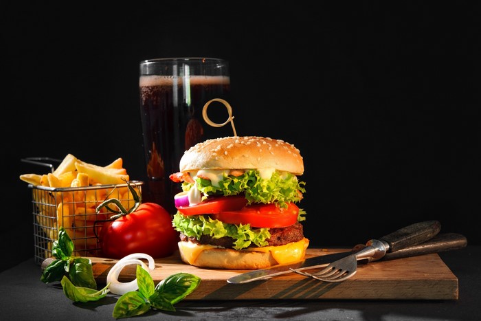 Burger with fries and soda on a cutting board
