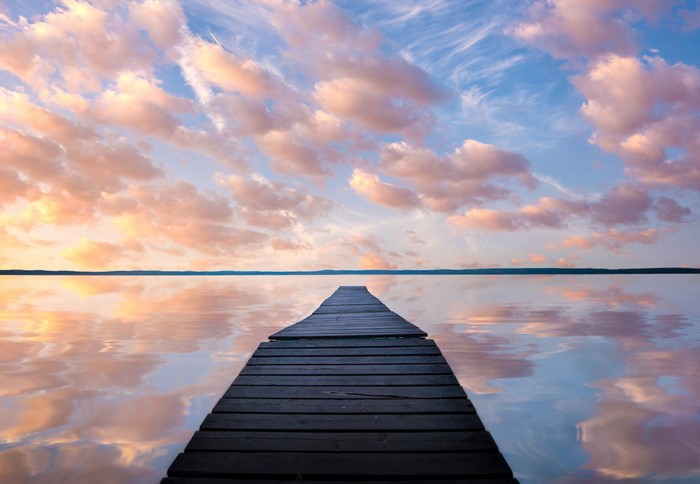 Wooden pier on a lake at sunset with colorful clouds