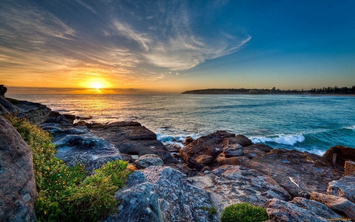 Sunset over the ocean with rocky shore