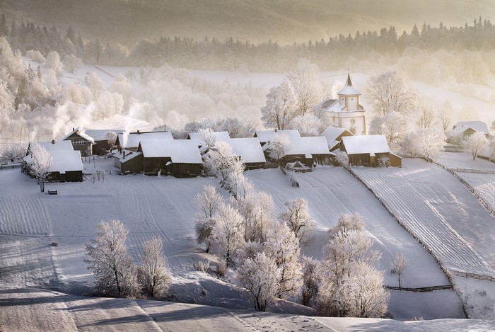 Snowy village with church in winter landscape