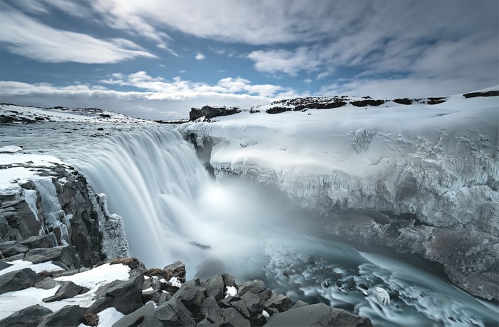Frozen waterfall in Iceland with snow and clouds