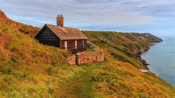 Wooden cabin on a grassy cliff overlooking the sea