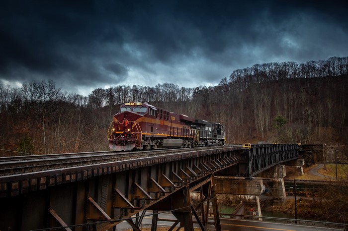 Train crossing a bridge under a stormy sky