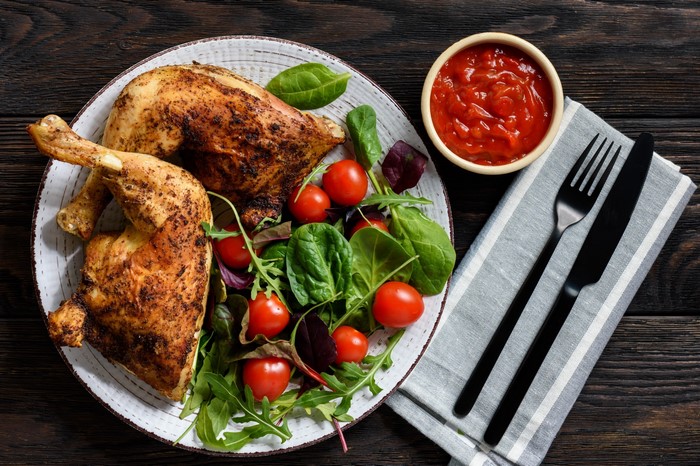 Roasted chicken legs with salad and tomato sauce
