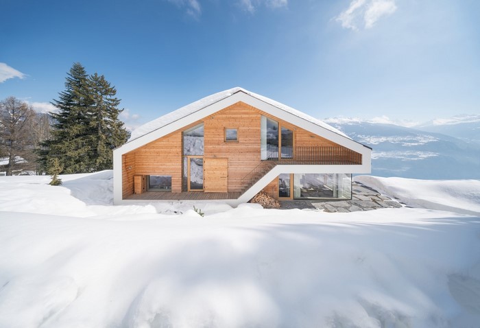 Modern wooden house in snowy mountains, Switzerland