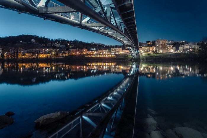 Bridge over river at night with city lights reflection
