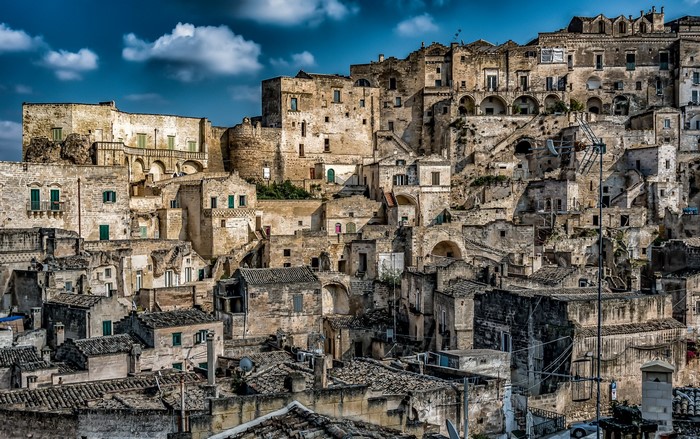 Ancient stone buildings on a hillside under a cloudy sky