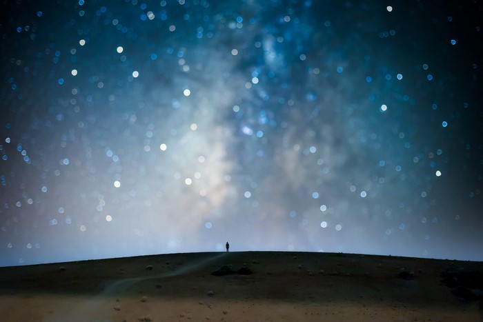 Person standing on a hill under a starry night sky