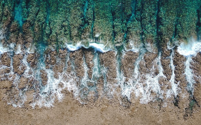 Aerial view of ocean waves crashing on rocky shore