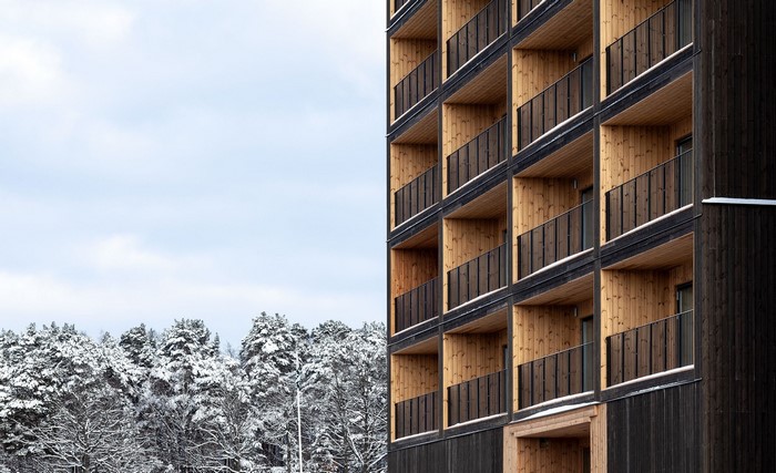 Modern wooden building with balconies and snow-covered trees