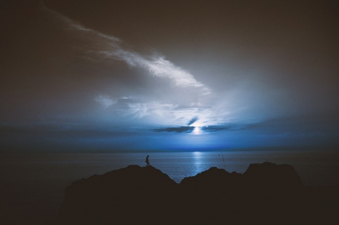 Silhouette of a person on rocks at sunset