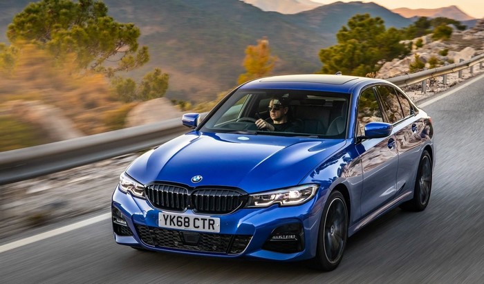 Blue BMW 3 Series Sedan driving on a mountain road