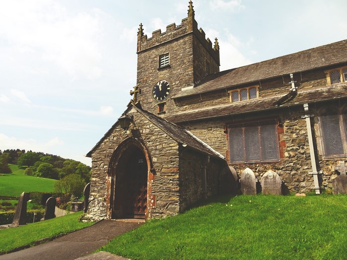 Stone church with clock tower and gravestones